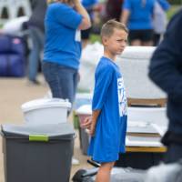 Young kid volunteering with family, watching at people unload